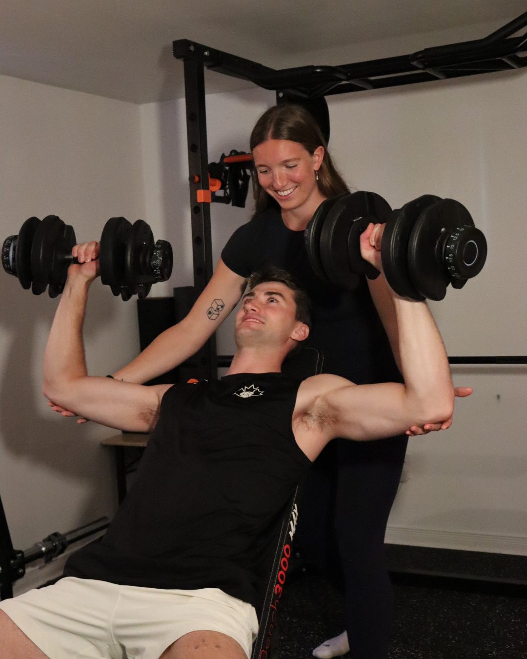 Maddie spotting a client through an incline dumbbell press in the gym.